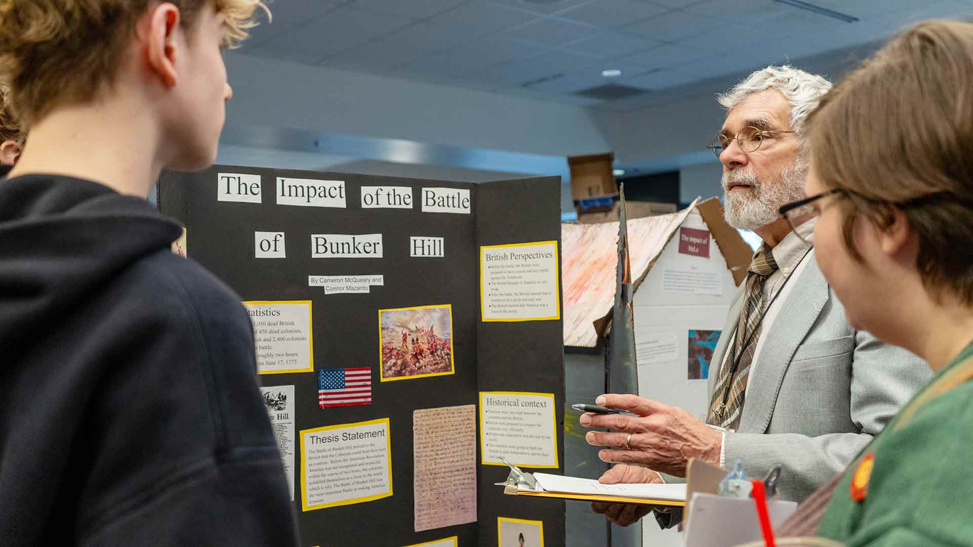 A judge, student and teacher discussing a presentation at National History Day..