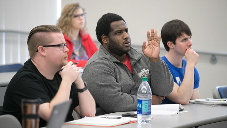 A student raises his hand to ask a question in his Ancient Egypt history class.