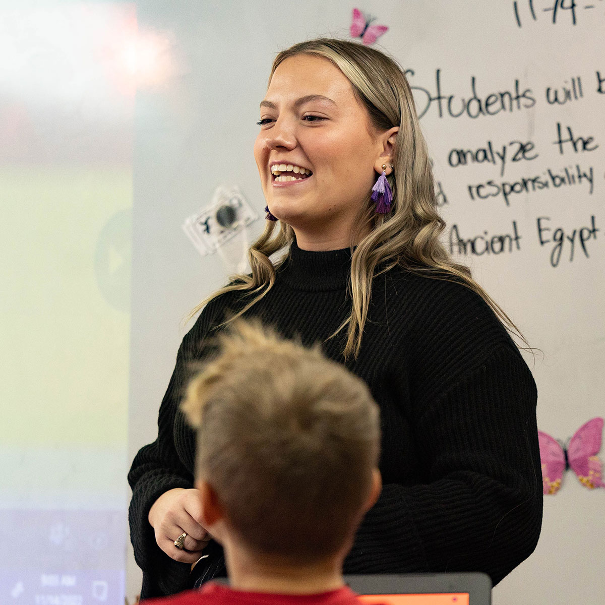 A middle school history teacher has a big smile while teaching her class.