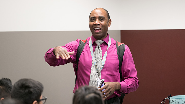 A teacher speaking to a group of students.