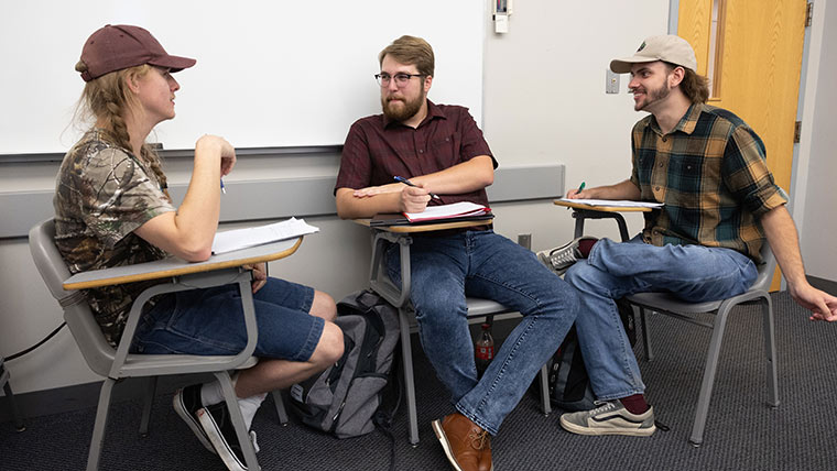 Three history education majors having a group discussion in class.