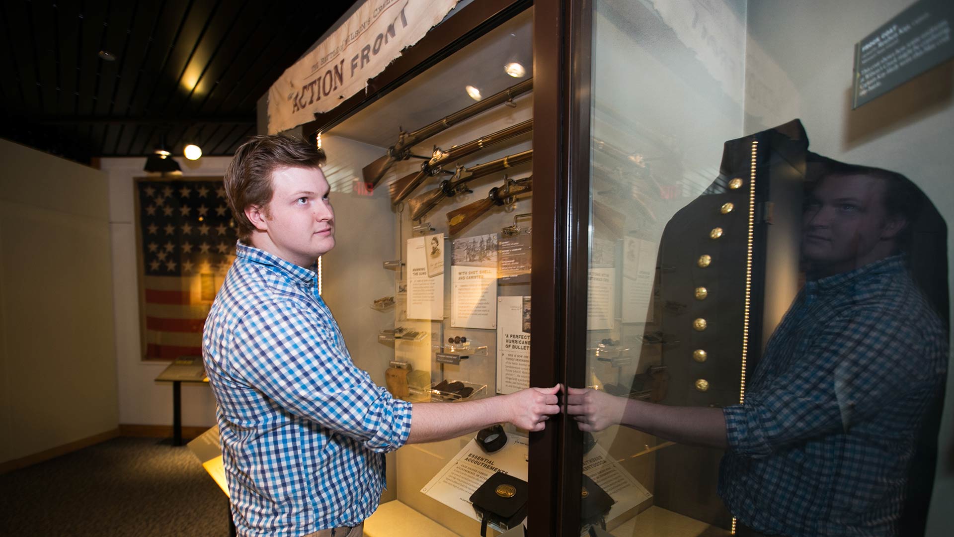 A history student looks into a case displaying a civil war uniform during his internship at Wilson's Creek National Battlefield