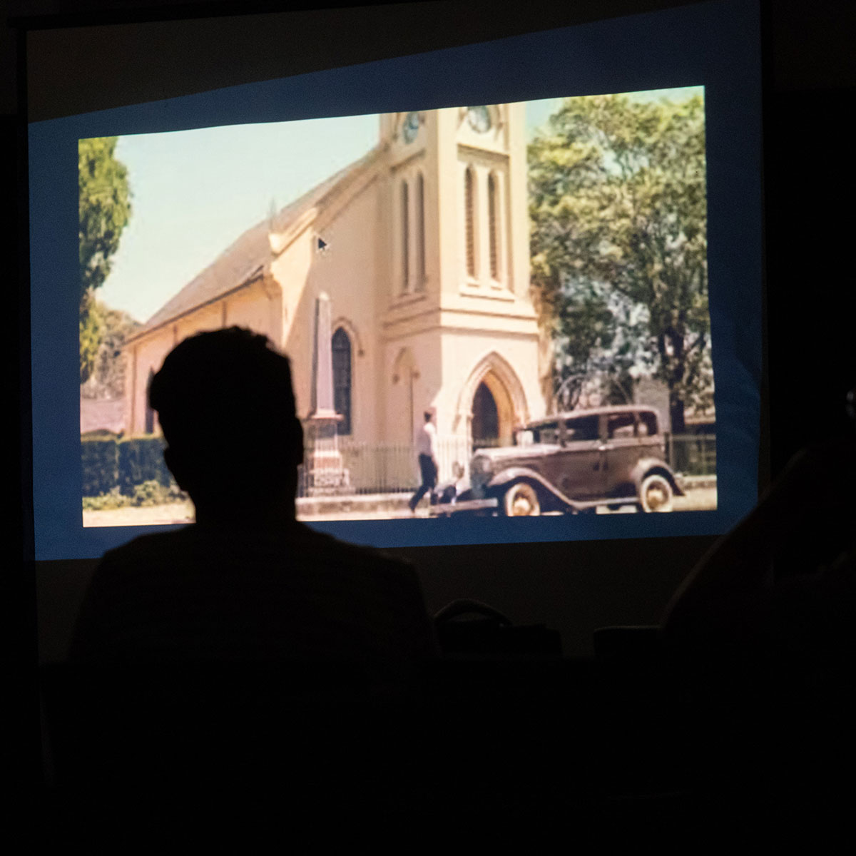 A judge watches a student's documentary project for the National History Day competition.