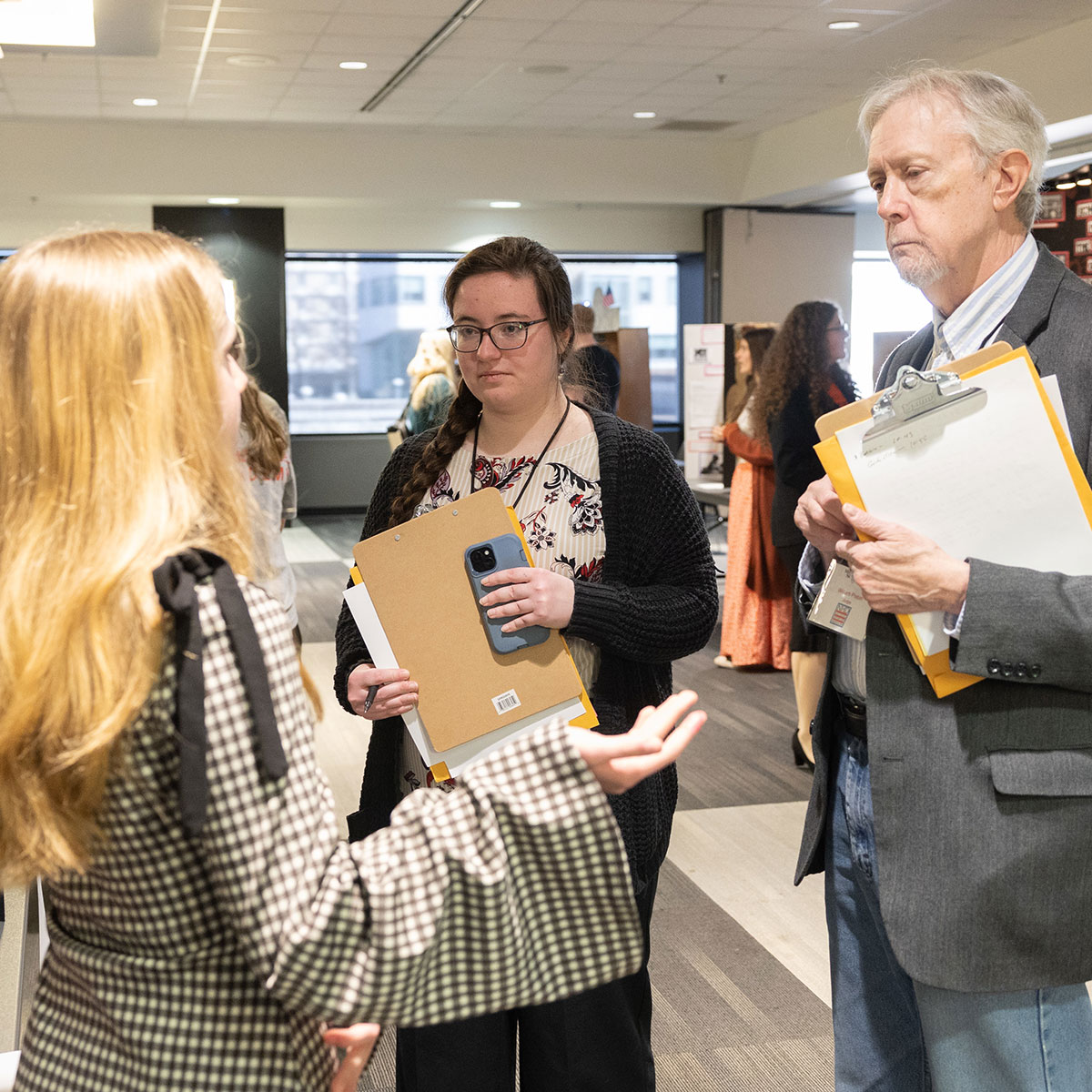 A student presents her National History Day project to two attentive judges.