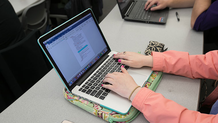 Student typing on a laptop in class.