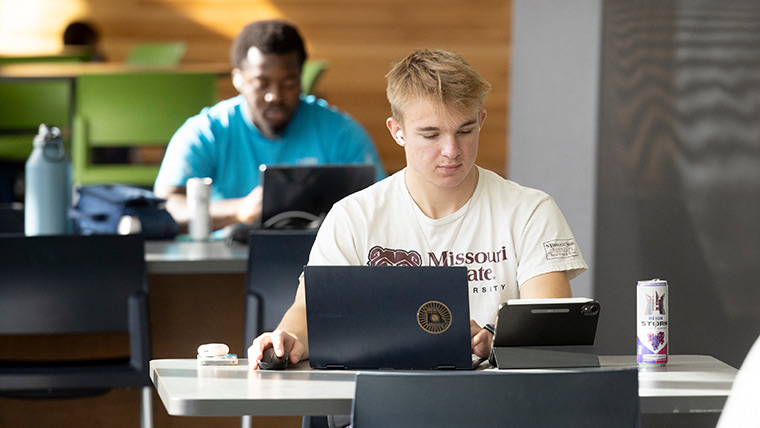 A student studying on his laptop in Meyer Library.